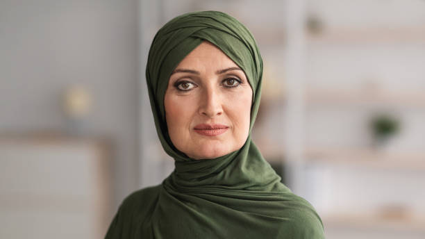 Middle-Aged Muslim Female Wearing Hijab Looking At Camera Posing Indoors Portrait Of Middle-Aged Muslim Female Wearing Hijab Looking At Camera Posing Standing Indoors. Beauty Of Middle-Eastern Women Concept. Headshot Of Senior Arab Lady. Panorama arab woman stock pictures, royalty-free photos & images