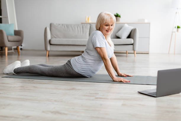 istock Senior woman stretching back on mat with pc 1331245920