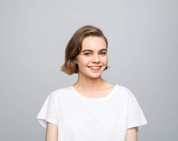 cheerful young woman in white t-shirt - diş telleri stok fotoğraflar ve resimler