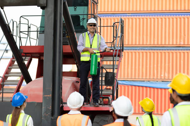 istock male engineer standing on crane car using fire extinguisher with factory workers in containers warehouse storage 1331249578