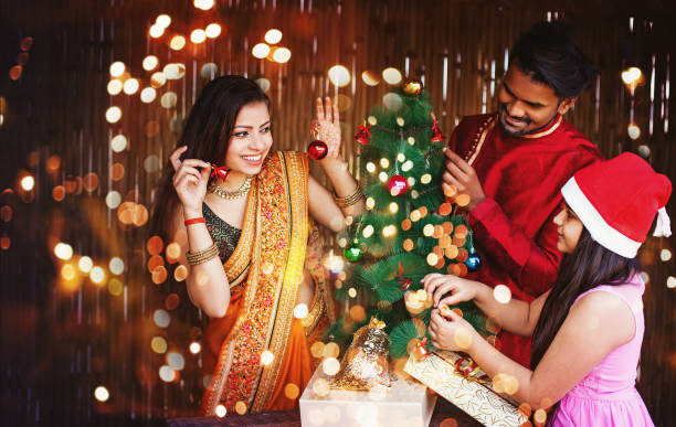 Indian family on Christmas Beautiful Indian family in ethnic clothes decorating Christmas tree for the New Year celebration at night beautiful traditional indian girl stock pictures, royalty-free photos & images