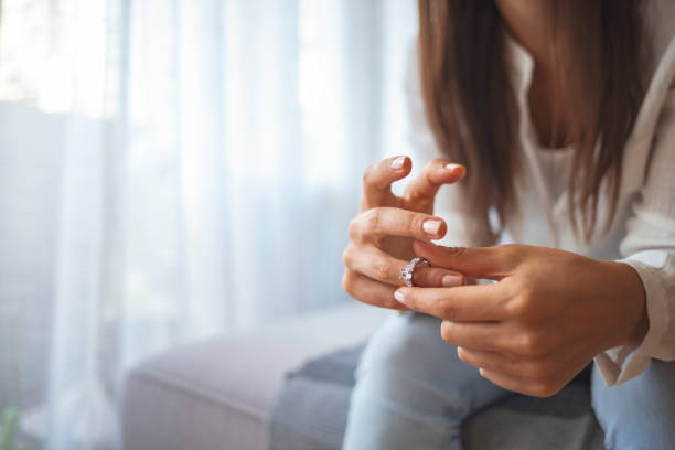 mujer infeliz sosteniendo anillo de bodas de cerca - divorcio fotografías e imágenes de stock