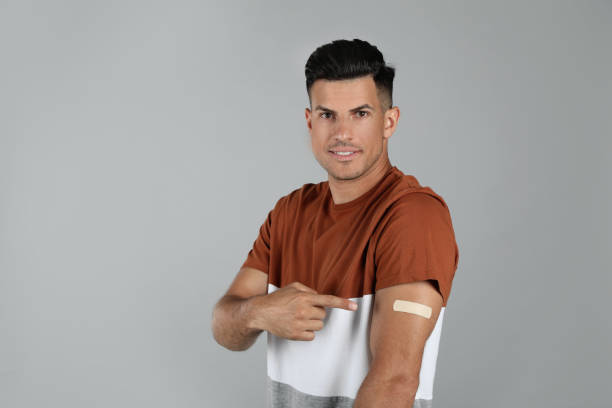istock Vaccinated man showing medical plaster on his arm against grey background 1331249865