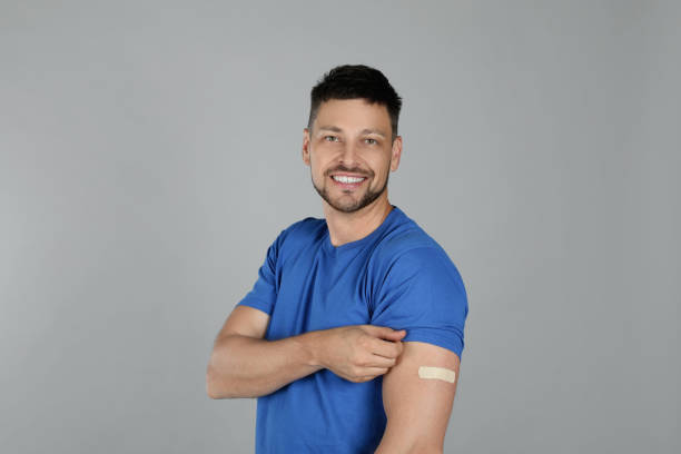 istock Vaccinated man with medical plaster on his arm against grey background 1331250708