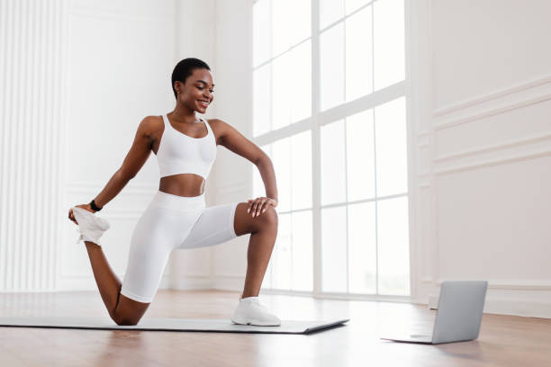 istock Cheerful black woman stretching leg muscles using pc 1331251317