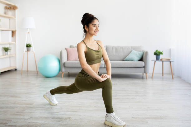 istock Pretty young Indian lady making lunge, doing strength exercises, working out booty and legs muscles at home 1331251328