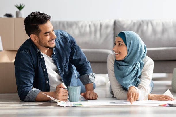 istock Creative muslim couple laying on floor with apartment scheme 1331252738