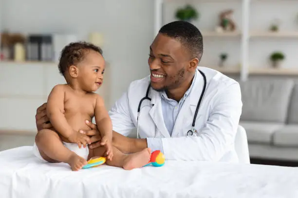 Photo of Portrait Of Smiling Black Doctor Making Check Up For Infant Baby Boy