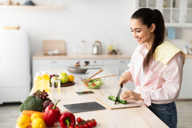 istock Woman cooking salad and using tablet at kitchen 1331254346