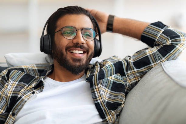istock Cheerful arab guy listening to music, using wireless headset 1331254791