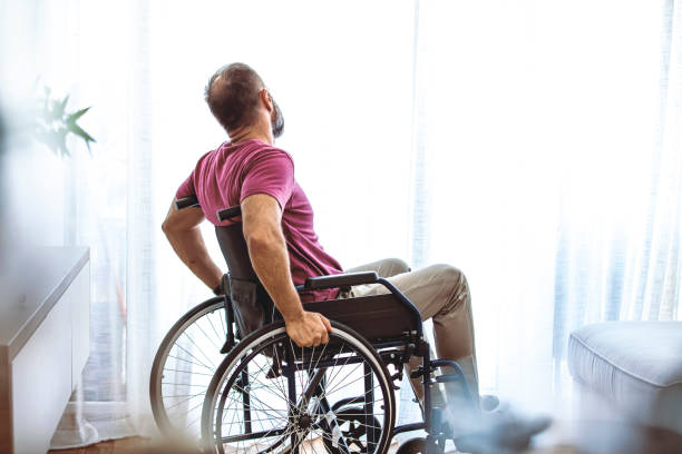 istock Disabled Person Sits in Wheelchair Against Window. 1331255788