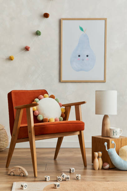 istock Creative composition of cozy scandinavian child's room interior with mock up poster frame, balance board, plush and wooden toys and hanging decorations. Neutral wall, carpet on the floor. Template. 1331256097