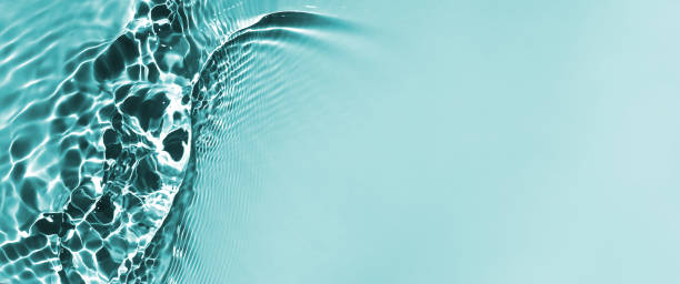 istock De-focused water waves in sunlight background. Aqua-mint liquid colored clear water surface texture with splashes bubbles with copy space.Trendy summer nature banner. 1331257304