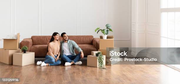 Family Relaxing On Floor In New Home With Cardboard Boxes Stock Photo - Download Image Now