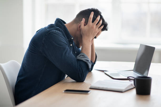 istock Exhausted arab man sitting in front of laptop, office interior 1331259420