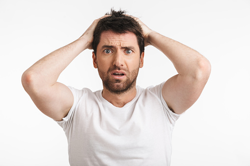 Image of muscular man 30s with bristle in casual t-shirt frowning and grabbing head isolated over white background