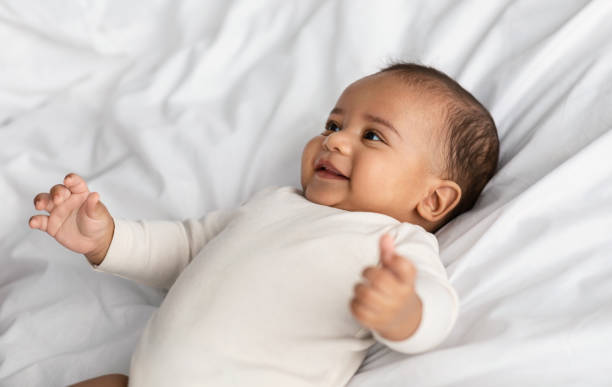 ベッドに横たわって笑っているかわいいアフリカ系アメリカ人の幼児 - newborn baby african ethnicity little girls ストックフォトと画像