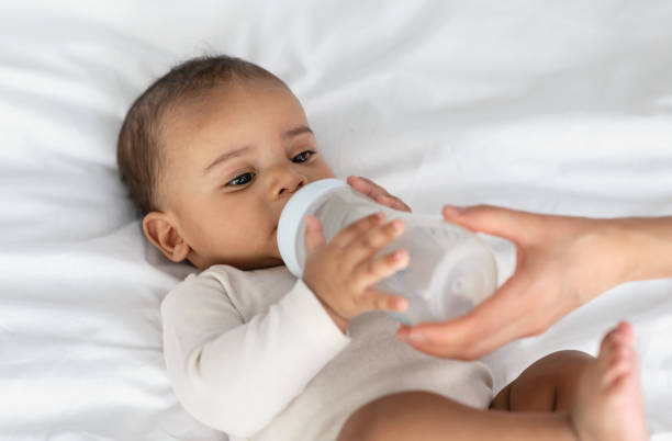 istock Cute little black baby drinking milk from bottle 1331259641