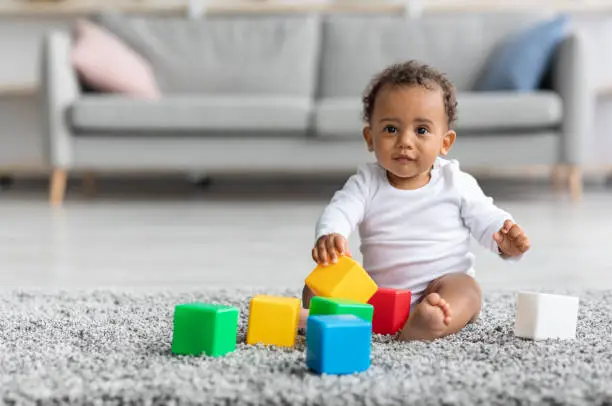 Photo of Adorable Black Infant Baby Playing With Stacking Building Blocks At Home