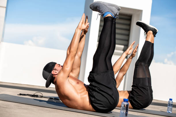 group of athletic men doing toe touch crunch workout exercise outdoors on building rooftop floor - 292 imagens e fotografias de stock