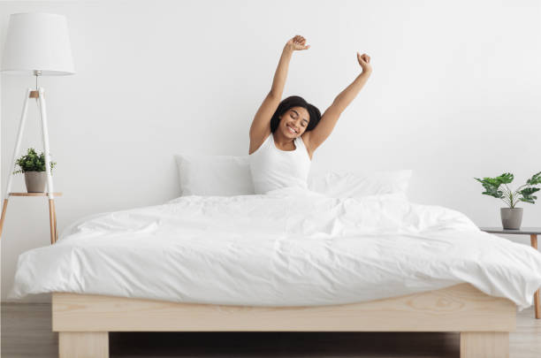 good start of new day. well-slept african american lady stretching arms after waking up, feeling happy - wake up stretching women black imagens e fotografias de stock