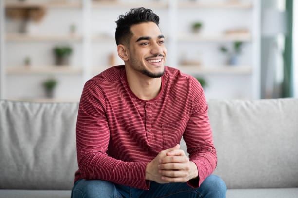 istock Joyful middle-eastern guy sitting on sofa at home 1331263462