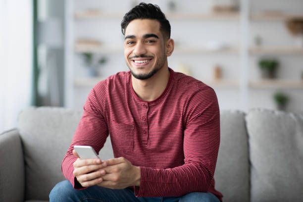 istock Positive arab guy using brand new cellphone, home interior 1331264916