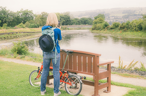 Woman in casual clothing taking a break on her phone while out cycling just outside the town of Dingwall on the Cromarty Firth of Scotland.