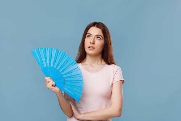 istock Pretty young lady with fan looking up, blue background 1331267760