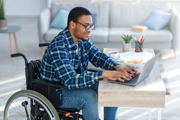 istock Online work for disabled people. Handicapped black guy in wheelchair using laptop for remote job at home 1331267825