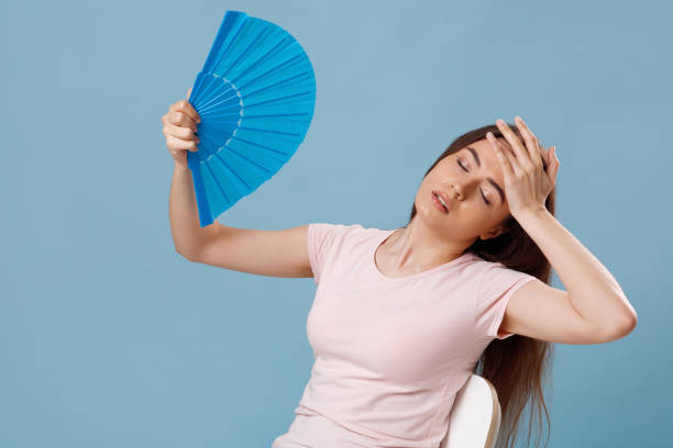 istock Sad millennial woman using paper fan over blue background 1331267951