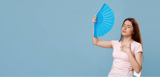 istock Sweaty beautiful lady with closed eyes cooling with hand fan 1331268363
