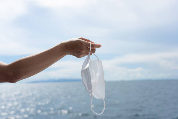 istock Female hand holding white face mask with sea background 1331269307