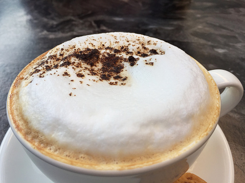 Frothy drink Cappuccino on the marble coffee table with cookie