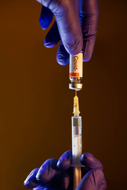 istock Hand with blue glove using syringe to draw Covid-19 Vaccine 1331270694