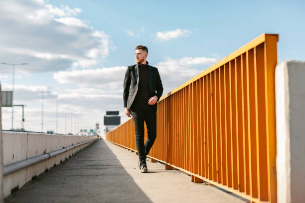 Well-dressed young businessman looking away while crossing the bridge