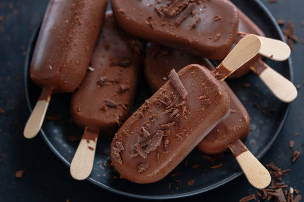 istock Dark chocolate ice cream popsicles with grated chocolate on dark plate. 1331272068