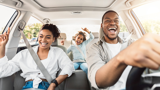 Feliz familia negra de tres cantando divirtiéndose montando un coche photo