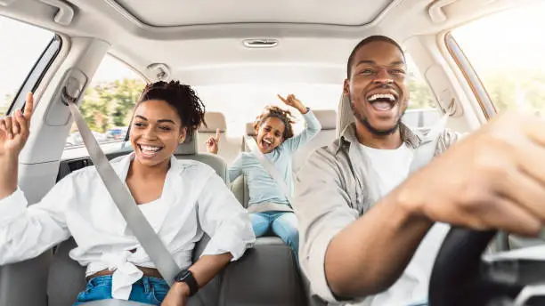 Photo of Happy Black Family Of Three Singing Having Fun Riding Car