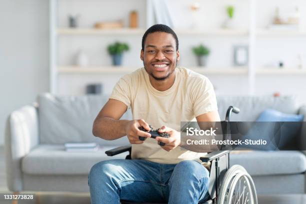 Cheerful Disabled Man In Wheelchair Enjoying Videogame On Playstation Having Fun At Home Stock Photo - Download Image Now