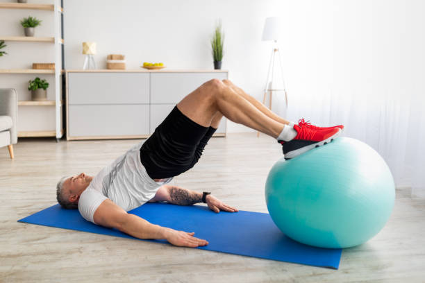 istock Exercises with ball at home during quarantine. Active mature man doing abs exercises in living room, copy space 1331274721