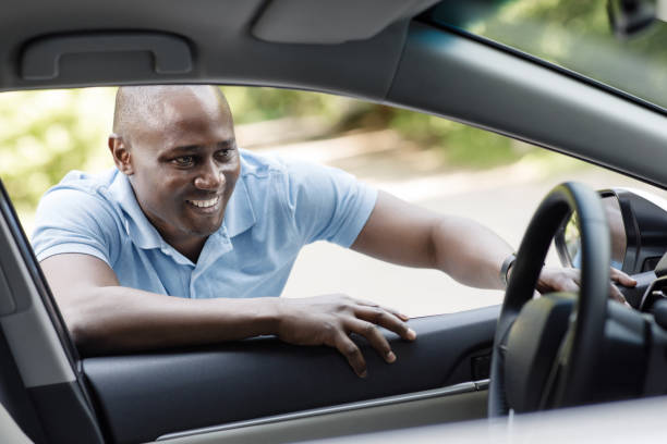 istock Happy african american man looking inside new car 1331279061