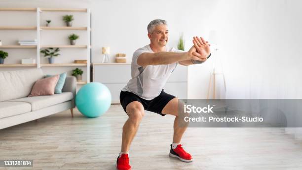 Strength Workout Concept Active Mature Man Doing Squats At Home Exercising In Living Room Panorama Free Space Stock Photo - Download Image Now