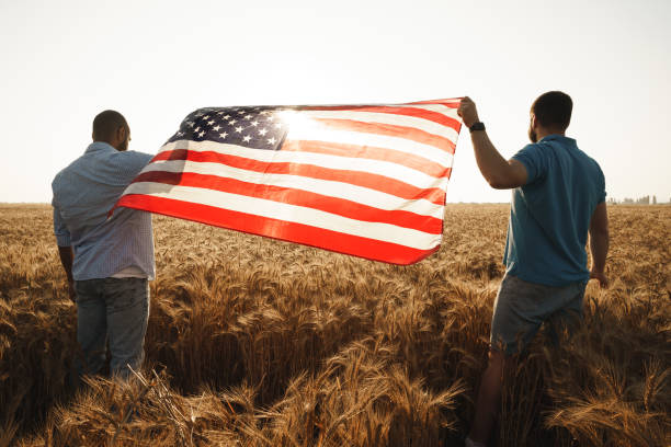 istock Two men patriots holding US flag above wheat field 1331282038