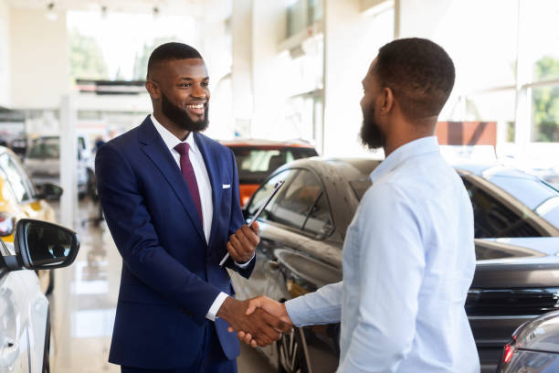 成功した取引の後、クライアントと握手笑顔の車の売り手 - car african descent shopping car dealership ストックフォトと画像
