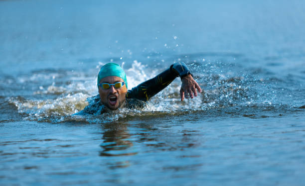 istock Professional triathlete swimming in river's open water. Man wearing swim equipment practicing triathlon on the beach in summer's day. 1331284037