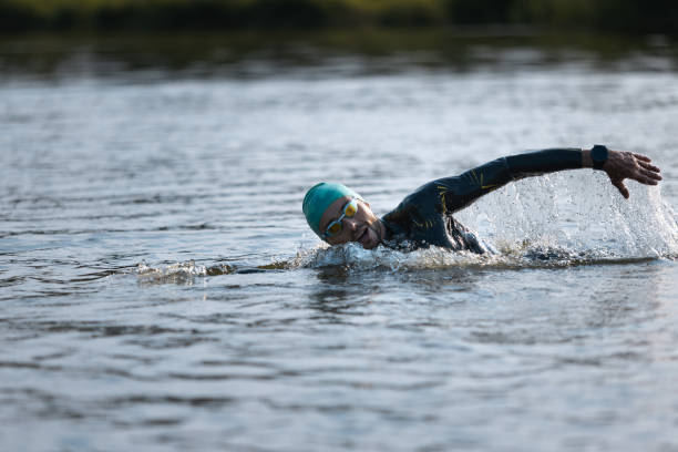 istock Professional triathlete swimming in river's open water. Man wearing swim equipment practicing triathlon on the beach in summer's day. 1331284055