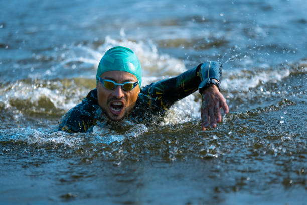 istock Professional triathlete swimming in river's open water. Man wearing swim equipment practicing triathlon on the beach in summer's day. 1331284068
