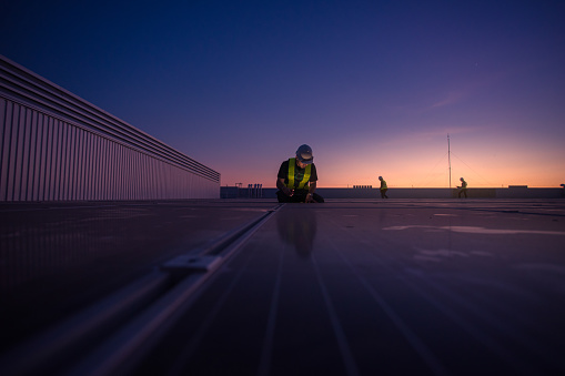 Technology solar cell, Engineer service check installation solar cell on the roof of factory on the morning. Silhouette technician with solar cell on the roof of factory under morning sky.