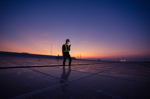 Technology solar cell, Engineer service check installation solar cell on the roof of factory on the morning. Silhouette technician with solar cell on the roof of factory under morning sky.